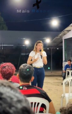 Anúncio com a Doutora Taty falando ao microfone para um público